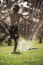 Little Boy Playing With Garden Sprinkler