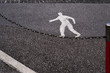 Pedestrian road sign appears to be tightrope walking across a chain