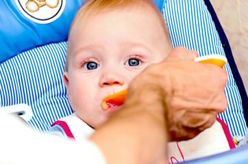 Baby boy eating in a high chair at home