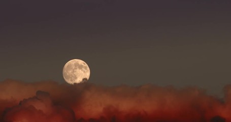 timelapse of full moon rising in dramatic clouds