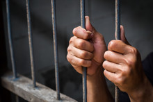 Soft Focus On Hands Of Man Behind Jail Bars. Vintage Or Retro Style. Selective Focus.
