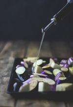 Olive Oil Being Drizzled On Sliced Eggplant On Baking Tray