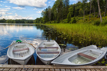Three Boats Near A Wooden Pier On The Lake In The Woods