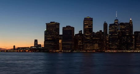 Wall Mural - New York City Lower Manhattan skyscrapers from sunset to dusk through nightfall with city lights. Time lapse cityscape view of the Financial District and East River