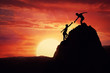 © psychoshadow - Hikers climbing on rock, mountain at sunset, one of them giving hand and helping to climb. Friendly assistance and support  in a dangerous situation.