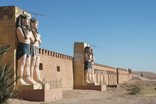 Statues Of Egyptian Male Figures Along A Wall And A Blue Sky