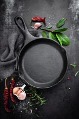 Poster - cast iron pan and spices on black metal culinary background, view from above