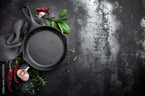 Cuadros en Lienzo cast iron pan and spices on black metal culinary background, view from above