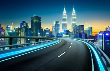 Wall Mural - Blue neon light highway overpass motion blur with city  skyline background , night scene .