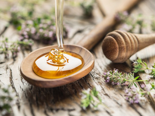 herbal honey pouring into the wooden spoon. spoon is on old wood