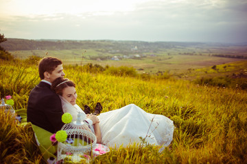 Wall Mural - White cage stands behind wedding couple lying on the field