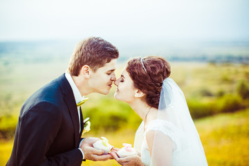 Wall Mural - Bride and groom touch each other noses while posing with white c