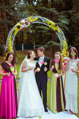 Wall Mural - Bride, groom and friends stand before the green wedding altar