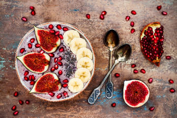 Wall Mural - Healthy fall and winter breakfast set. Acai superfoods smoothies bowl with chia seeds, pomegranate, sliced banana, fresh figs and hazelnut butter. Overhead, top view.