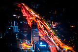 Fototapeta Boho - Tilt shift blur effect. Futuristic night cityscape aerial view panorama with illuminated skyscrapers and city traffic across streets. Bangkok, Thailand