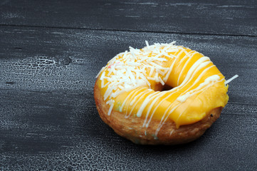 Fresh tasty donuts in soft colorful glaze on a black and white grunge  wooden background