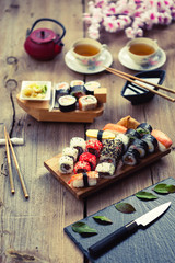 Wall Mural - A variety of sushi and green tea set on rustic wooden table.