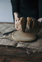 Woman Slicing Freshly Baked Rye Bread On A Rustic Wooden Table