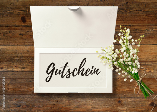 Obraz na plátně Gutschein - Text in Box mit Maiglöckchen auf rustikalem Holztisch