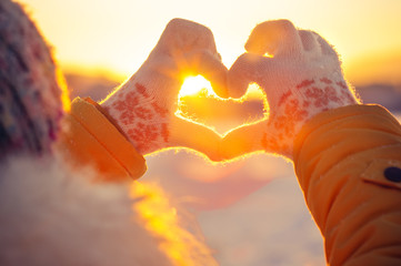 woman hands in winter gloves heart symbol shaped lifestyle and feelings concept with sunset light na