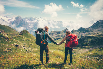 Wall Mural - Couple Man and Woman with backpack holding hands mountaineering Travel Lifestyle summer vacations concept mountains and clouds landscape on background
