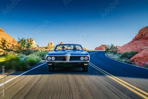 Obraz na plátne couple driving together in cool vintage car through desert