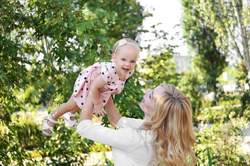 Wall Mural - Happy mother with daughter resting in park on sunny day