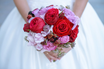 Beautiful bride is holding a wedding colorful bouquet. Beauty of colored flowers. Close-up bunch of florets. Bridal accessories. Female decoration for girl. Details for marriage and for married couple