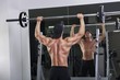 Handsome powerful athletic man doing barbell shoulder press exercise. Strong bodybuilder with perfect muscles.