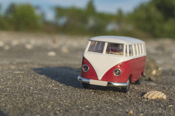 travel concept with classic van miniature on sandy beach over bl