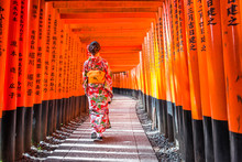 Women In Kimono Stand At Red Torii Gates In Fushimi Inari Shrine, One Of Famous Landmarks In Kyoto, Japan