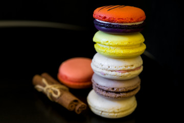 Wall Mural - view from top point to vivid colored macaroons in stack on each other on black background/more free space/different focus point/landscape orientation