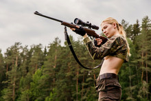 Pretty Hunter Girl Aiming With Hunting Rifle In The Outer Wood. Carbine With Optical-sight