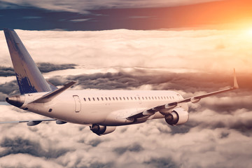 Wall Mural - White airplane flying higher clouds at sunset