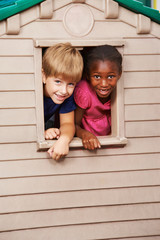 two children looking through window in playhouse