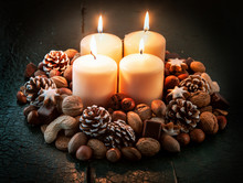 Four Wide Candles Surrounded By Nuts And Cones