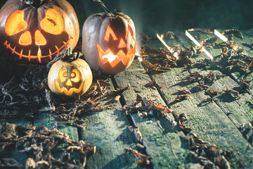 Wall Mural - Halloween pumpkins at wood background. Carved scary faces of pumpkin.