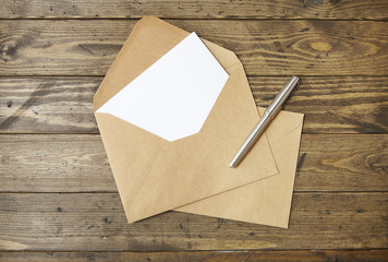 an open brown envelope with letter and writing pen on a rustic wooden desk top background