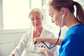 Canvas Print - nurse with stethoscope and senior woman at clinic