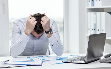 stressed businessman with papers in office