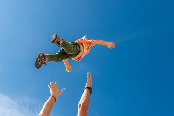 The elder brother throws his younger  on the beach against the backdrop of the sea. Happy carefree childhood