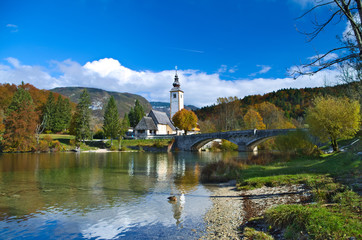 Autumn view of the stone bridge and the Church of St. John the Baptist at Lake Bohinj (Bohinjsko jezero), Slovenia
