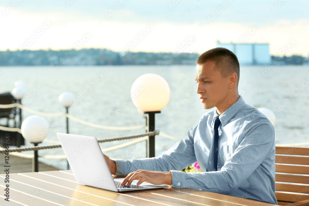 Businessman working on laptop, outdoors