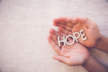 hope wooden word on praying hands , gratitude, faith concept