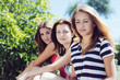 © stormy - Three beautiful girls laughing together sitting on grass outdoors in a park