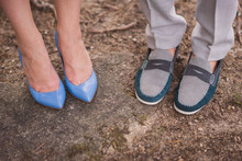 Stylish Couple. Closeup Of Female And Male Feet In Blue And Turquoise And Grey Casual Shoes On Natural Background.
