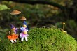 Vier kleine Wichtel sitzen im Moos unter Pilzen 
