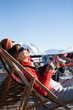 © plprod - femme avec un café dans un transat sur une terrasse de restaurant dans les montagnes enneigées