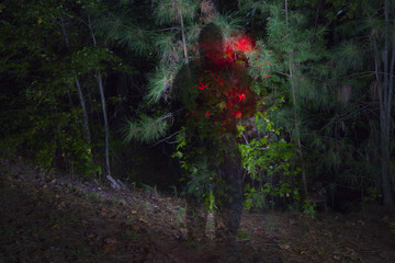 A dark shadowy figure at night in a forest.