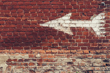 White Arrow Painted On Red Brick Wall